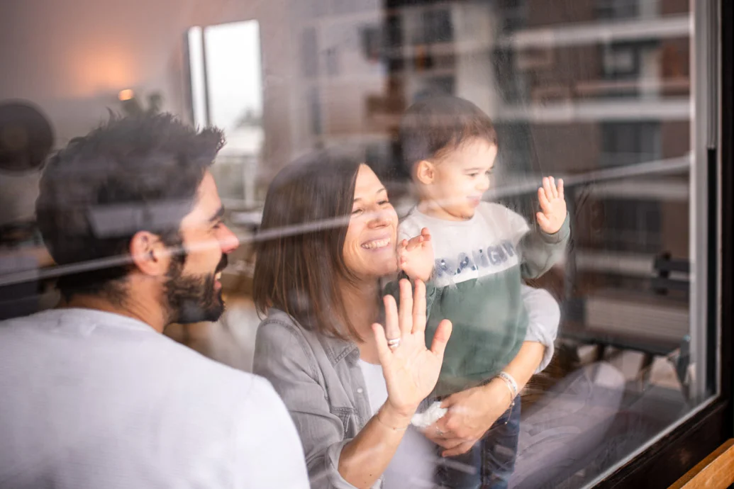 Famille souriante qui regarde dehors par la fenêtre lors d'un shooting photo en famille en Essonne