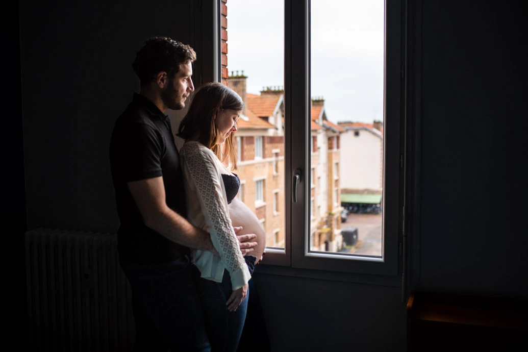 Femme enceinte tendrement enlacée par le futur papa lors d'un shooting photo grossesse à Paris