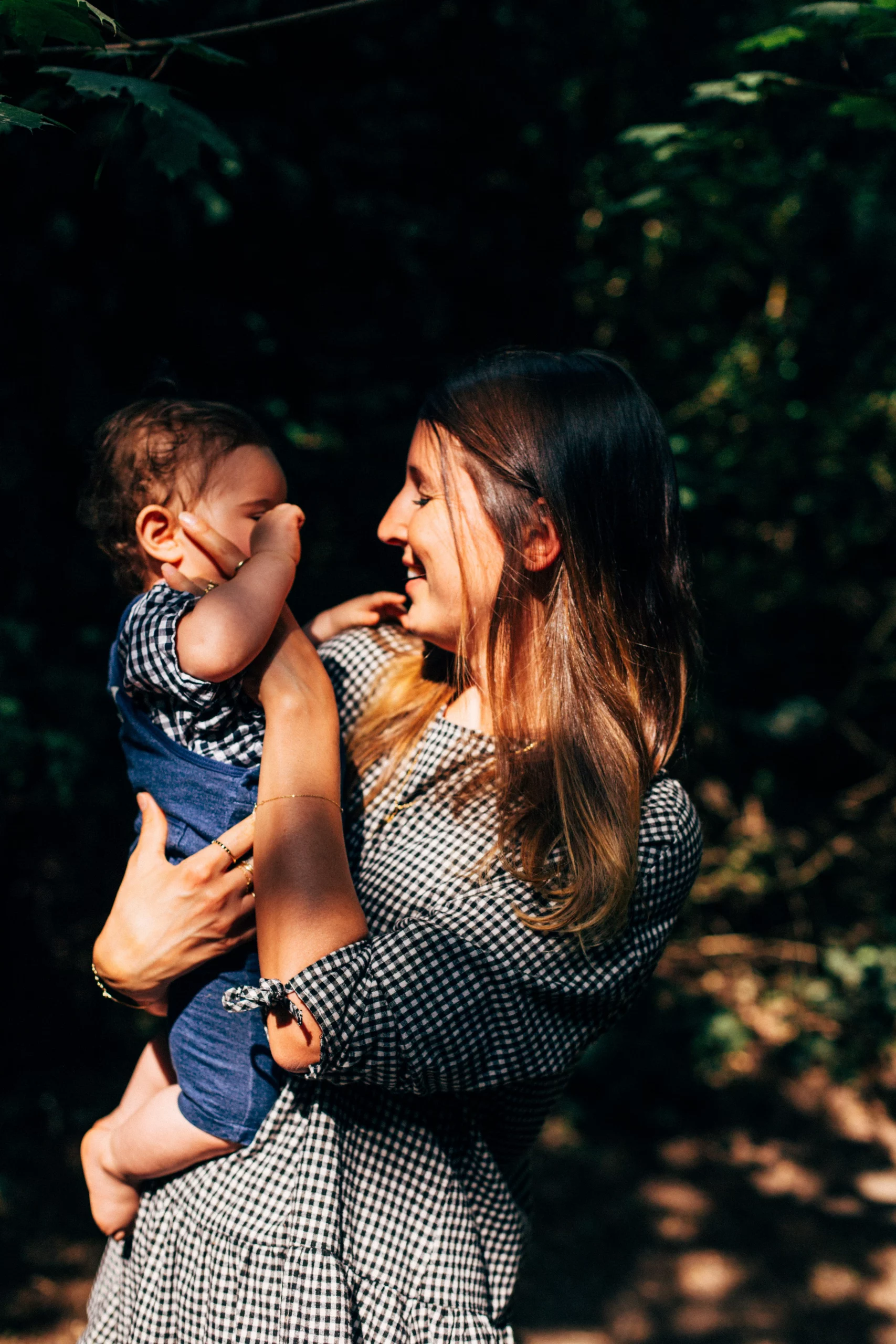 jeu de lumière pendant un autoportrait d'une maman photographe en Ile de France jouant avec son bébé dans ses bras