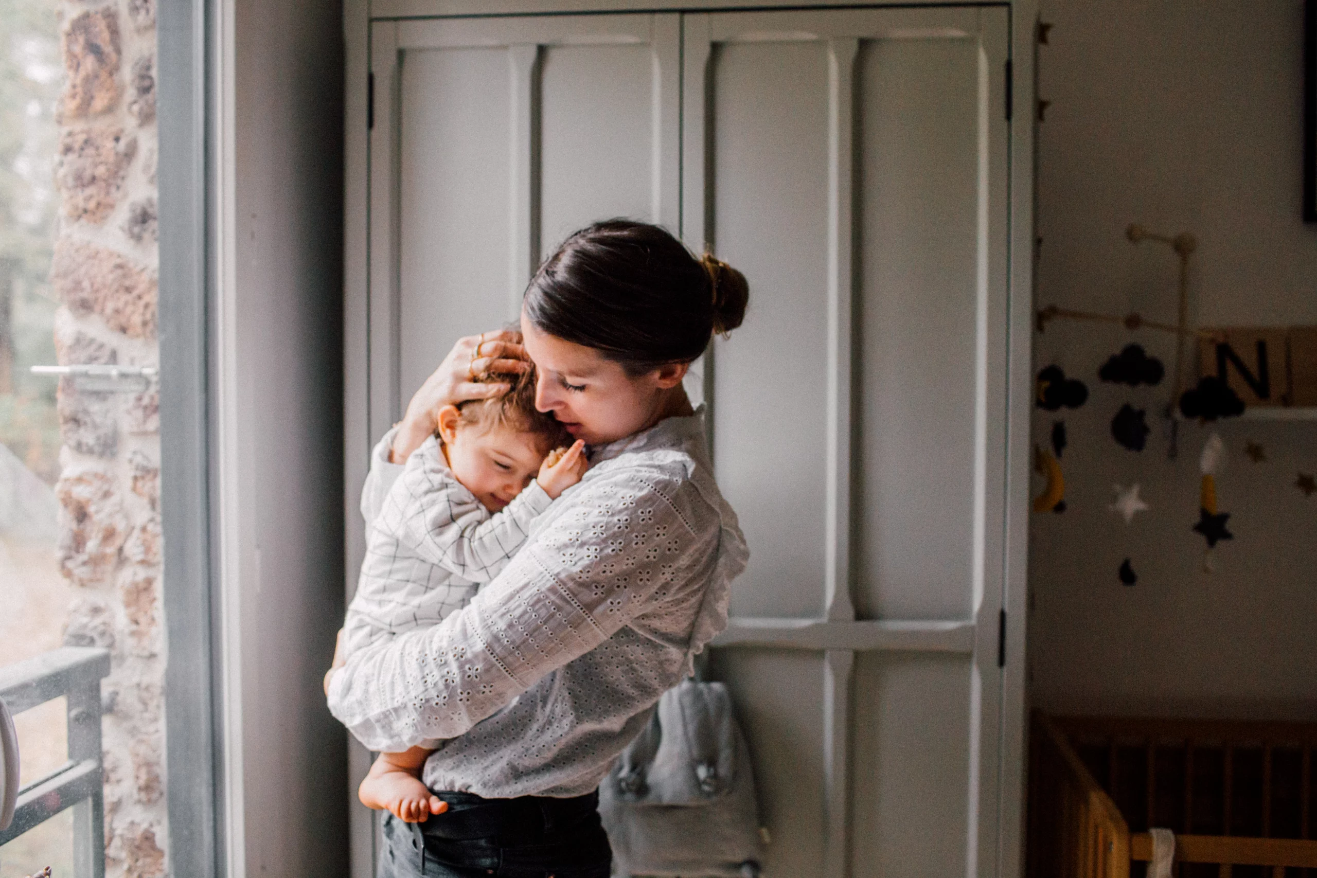 maman photographe qui serre son enfant contre son coeur lors d'une séance photo à domicile à paris
