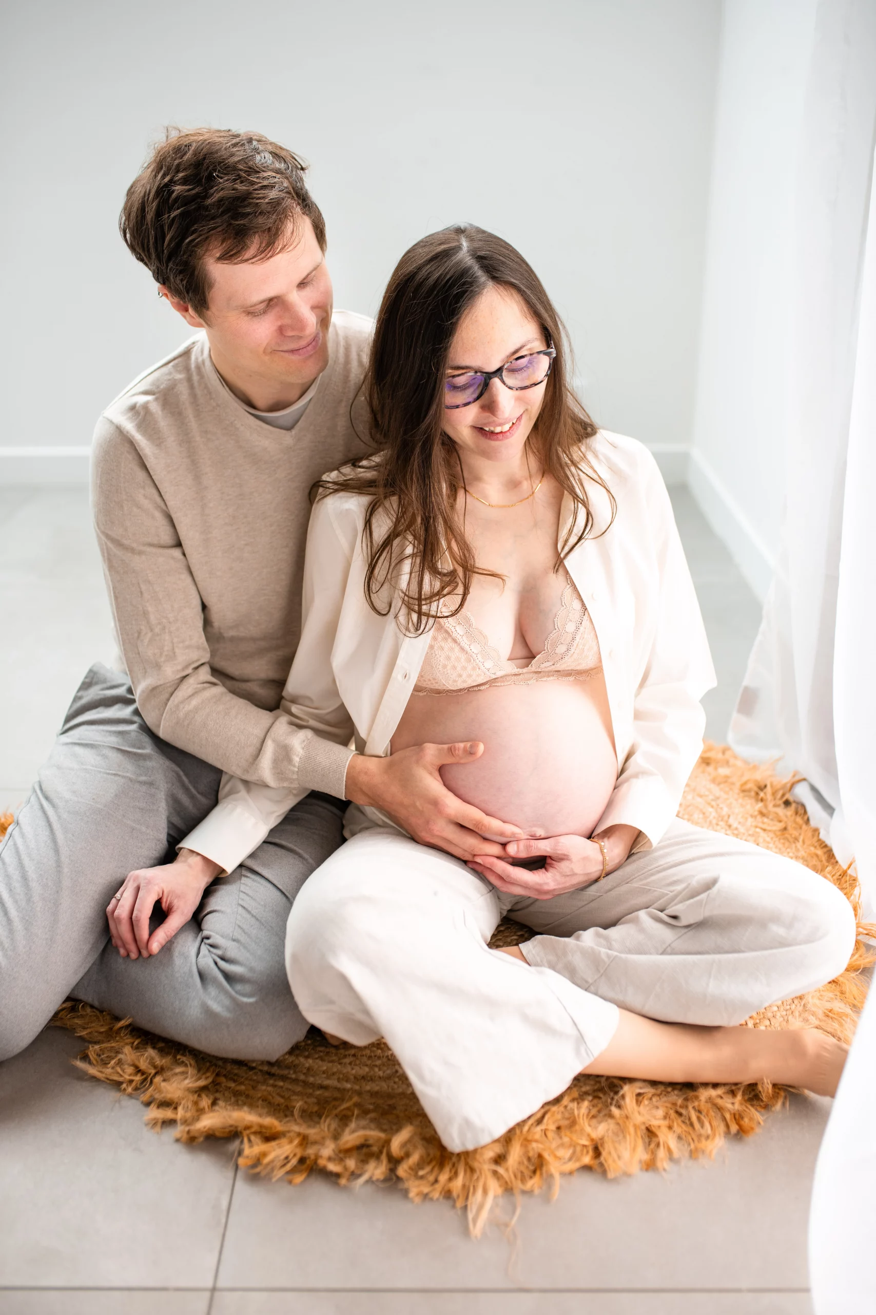 futur papa qui caresse le ventre de sa femme enceinte lors d'un shooting photo