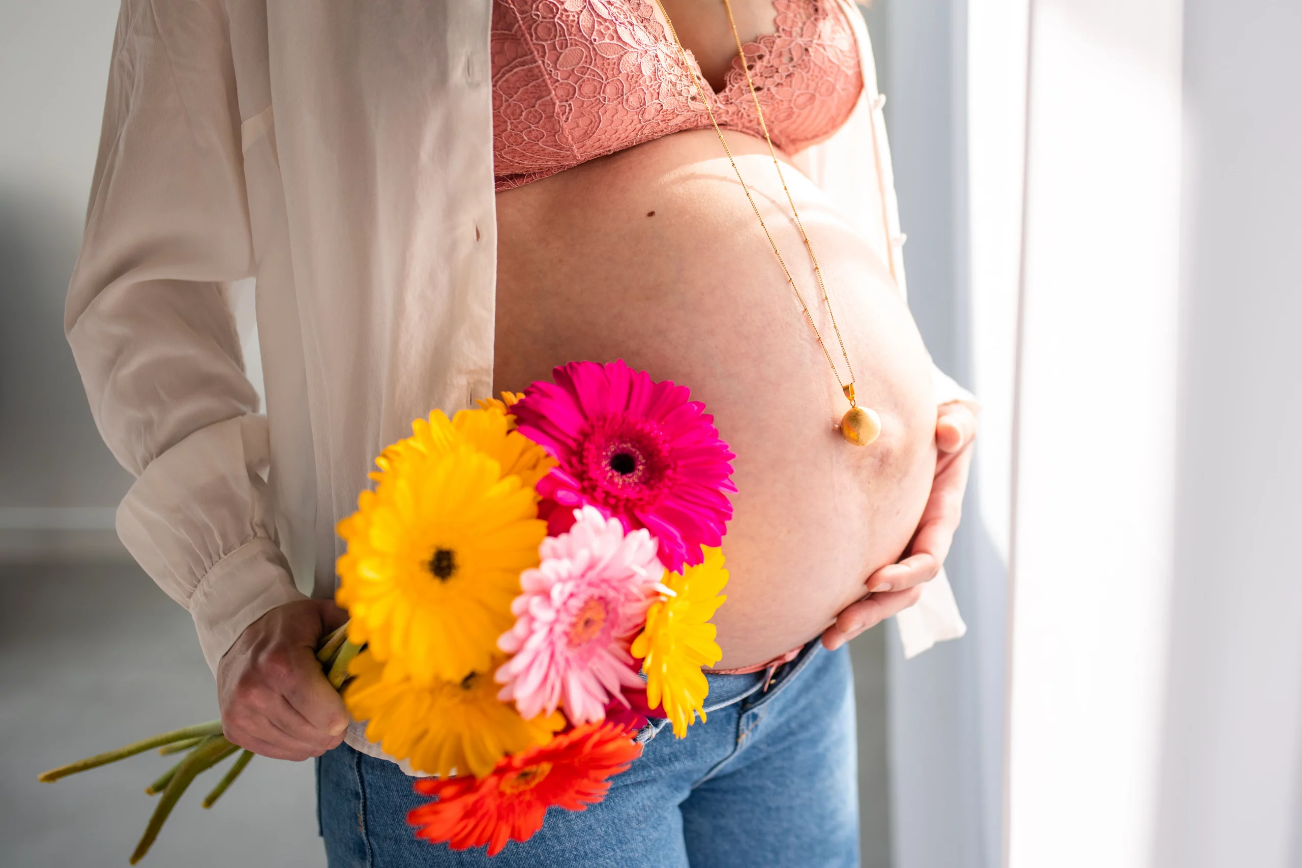 ventre de future maman sublimé par un bouquet de fleurs lors d'une séance photo en studio