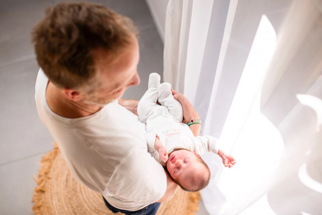 nouveau né endormi dans les bras de son papa pendant une séance photo naissance