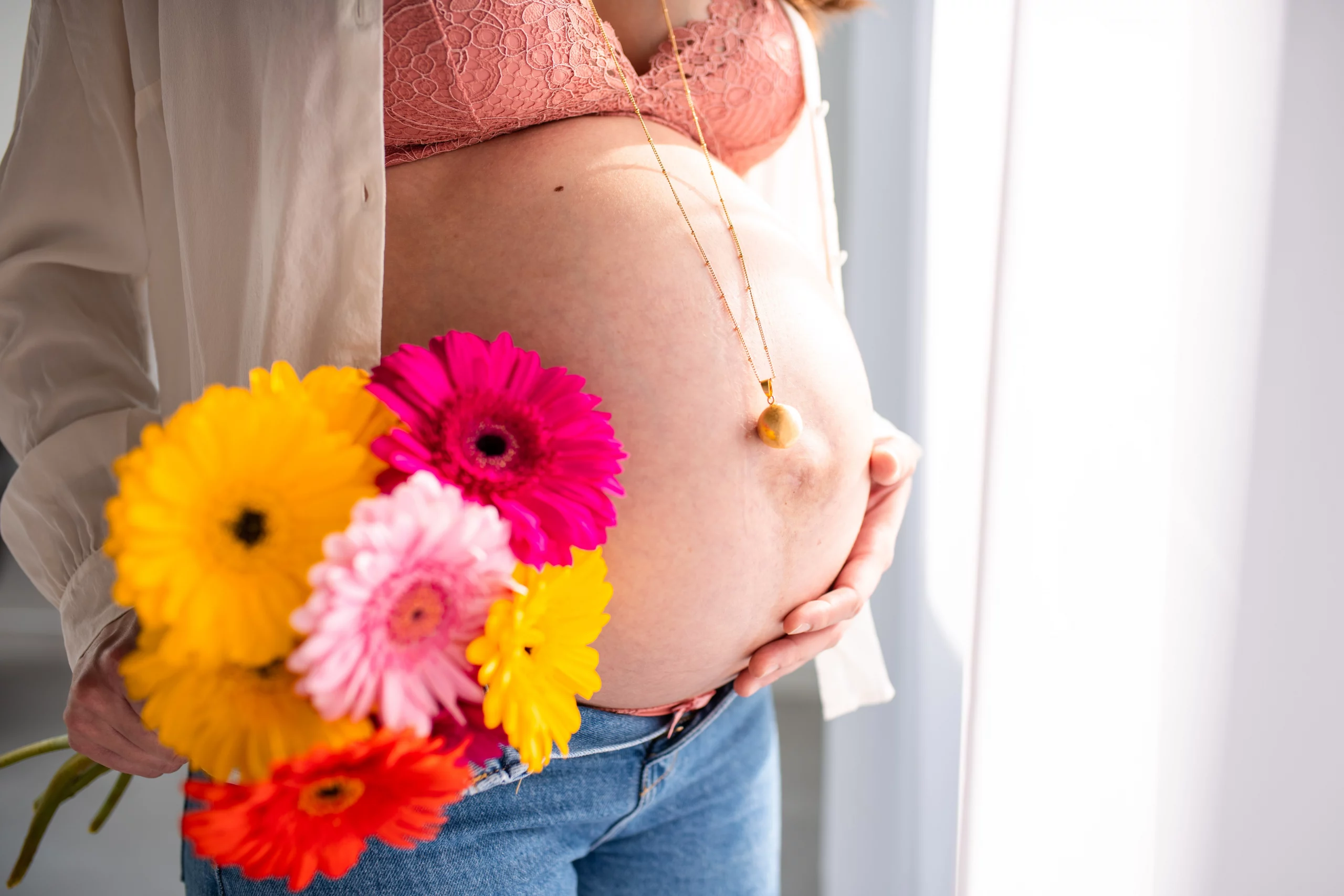 Ventre rond de future maman mis en valeur par la lumière 