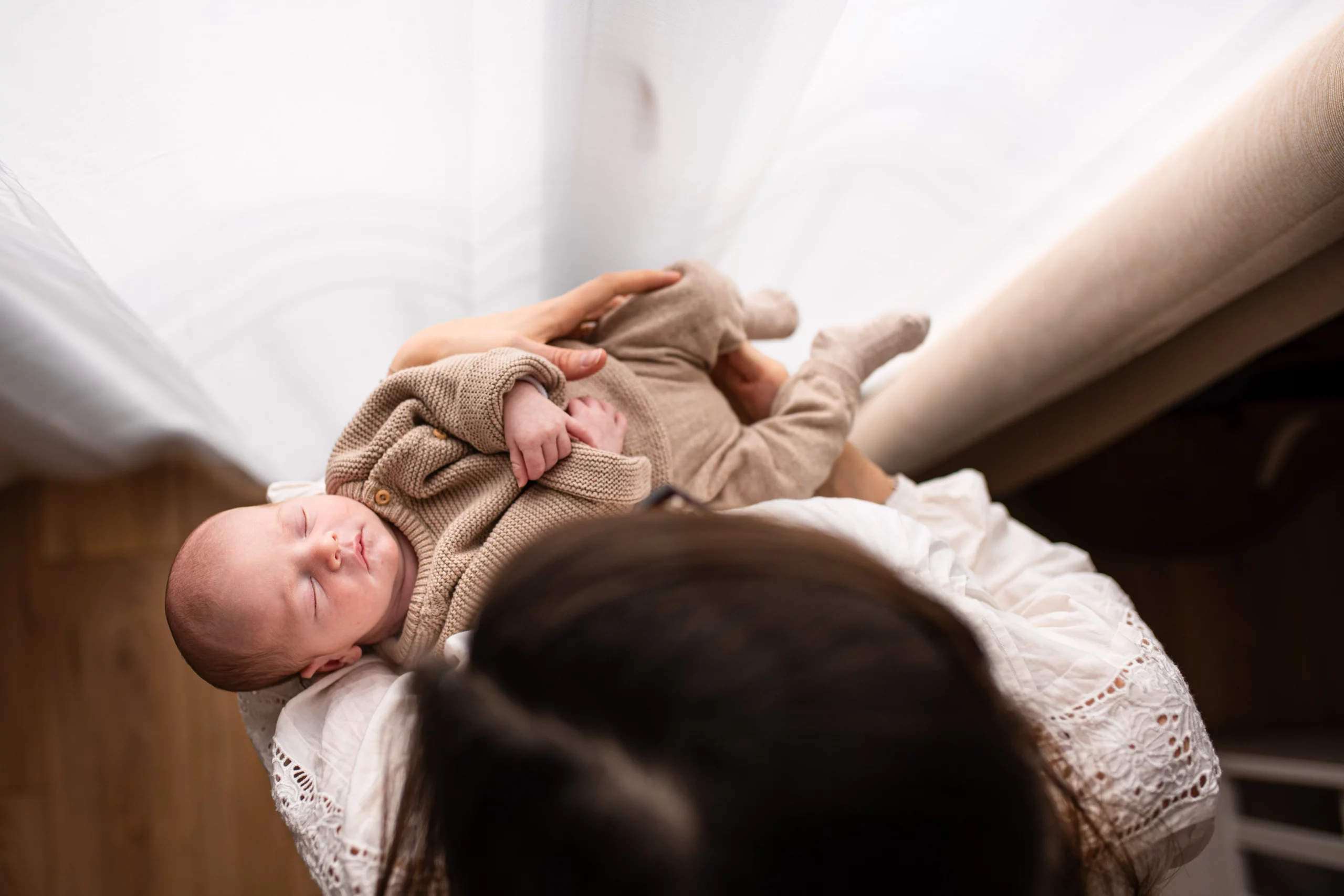 Photographe naissance Massy, Nouveau né endormi paisiblement dans les bras de sa maman pendant une séance photo naissance à Massy