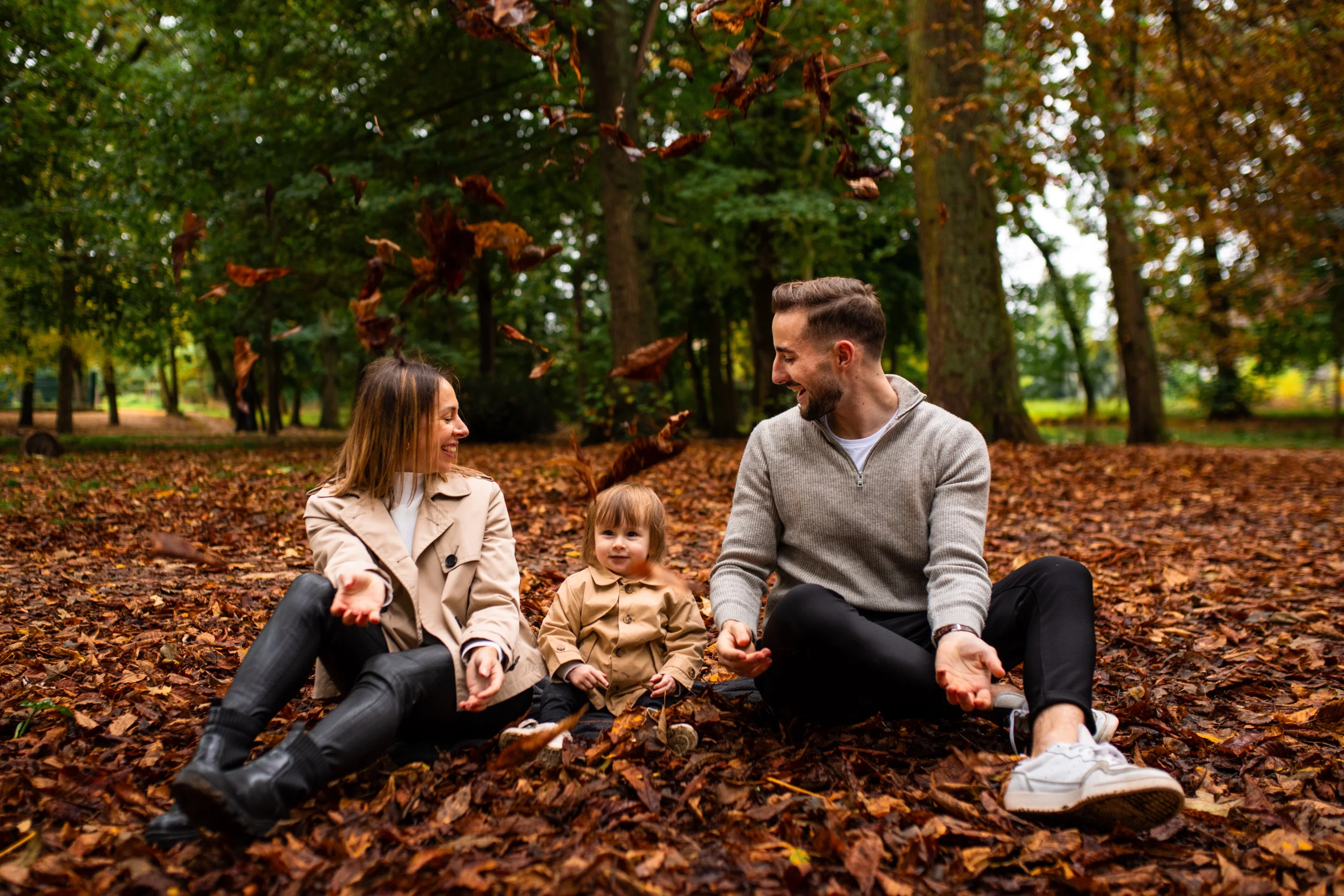 Famille qui joue avec des feuilles mortes dans un parc en Essonne