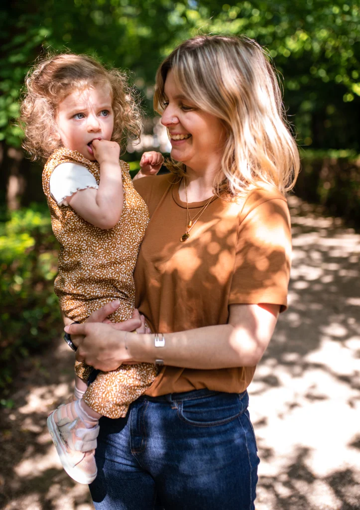petite fille dans les bras de sa maman souriante