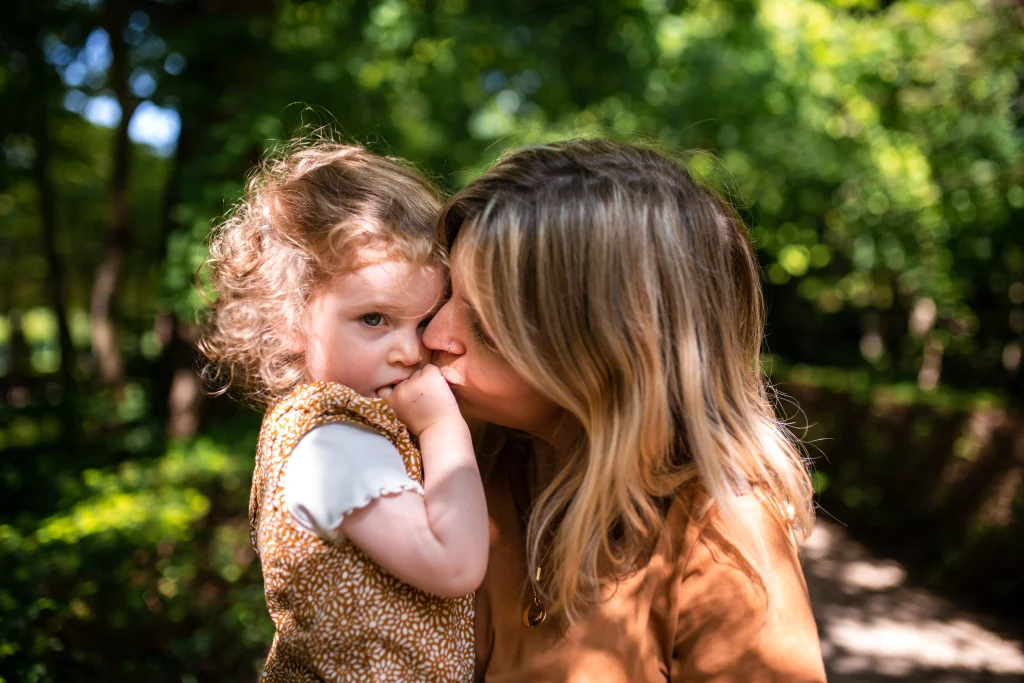 maman embrassant sa fille sublimé par la lumière et les ombres en forêt