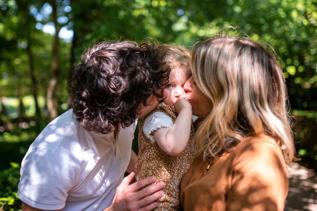 parents embrassant leur petite fille lors d'une balade en forêt