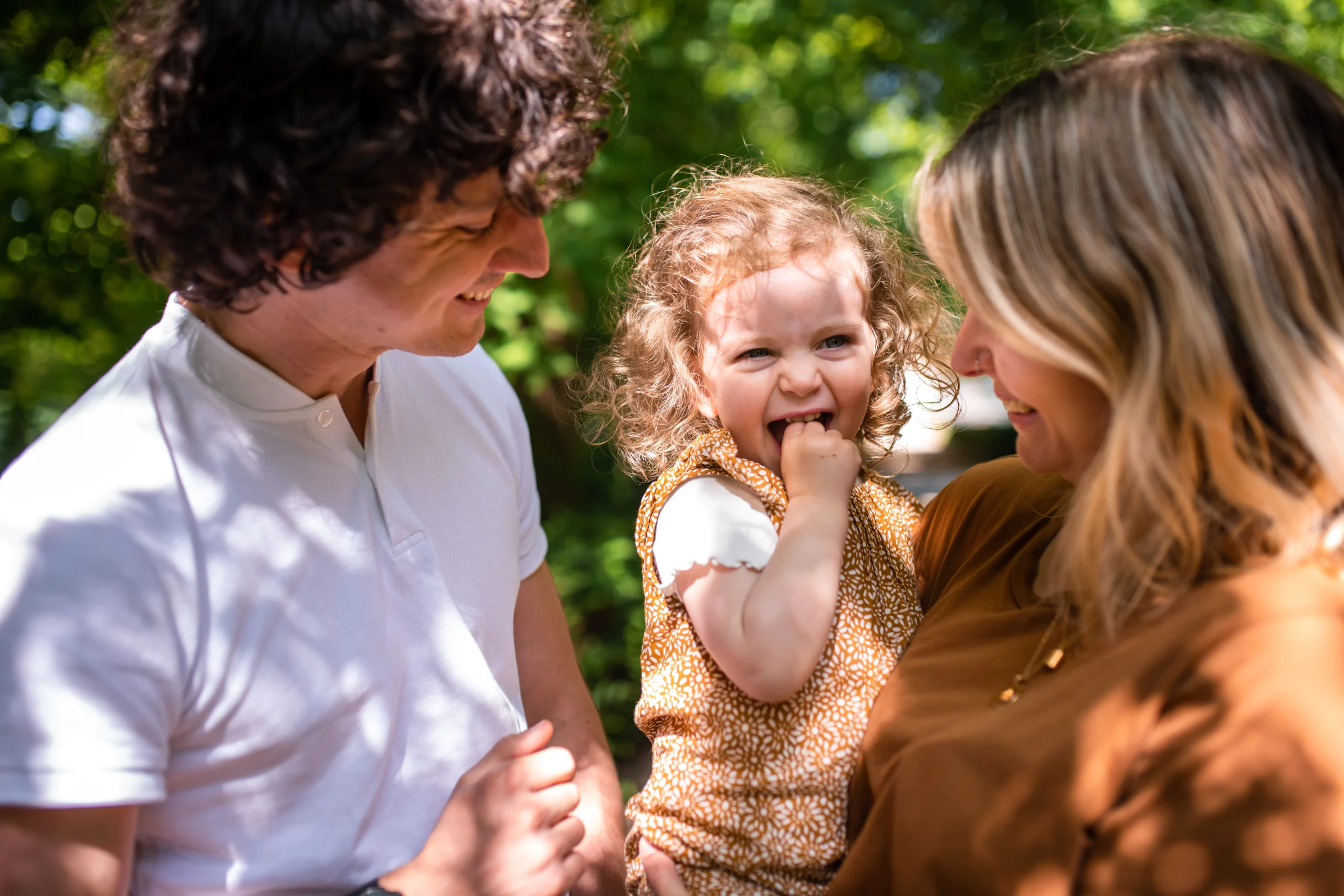 petite fille souriante dans les bras de sa maman lors d'une séance photo famille